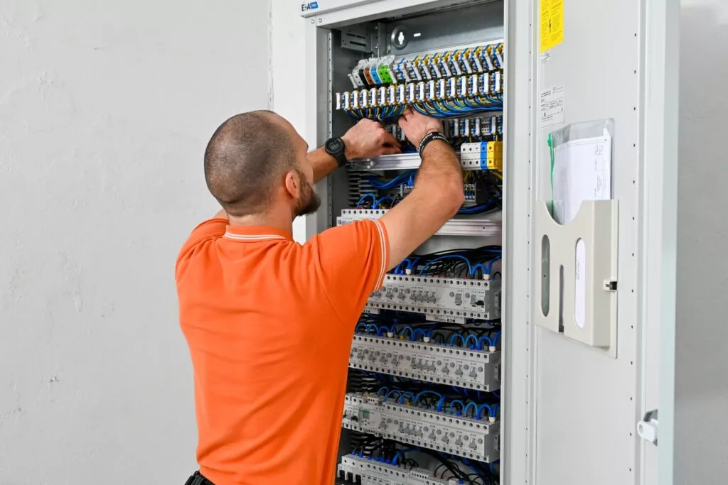 Człowiek montujący sprefabrykowaną rozdzielnicę elektryczną